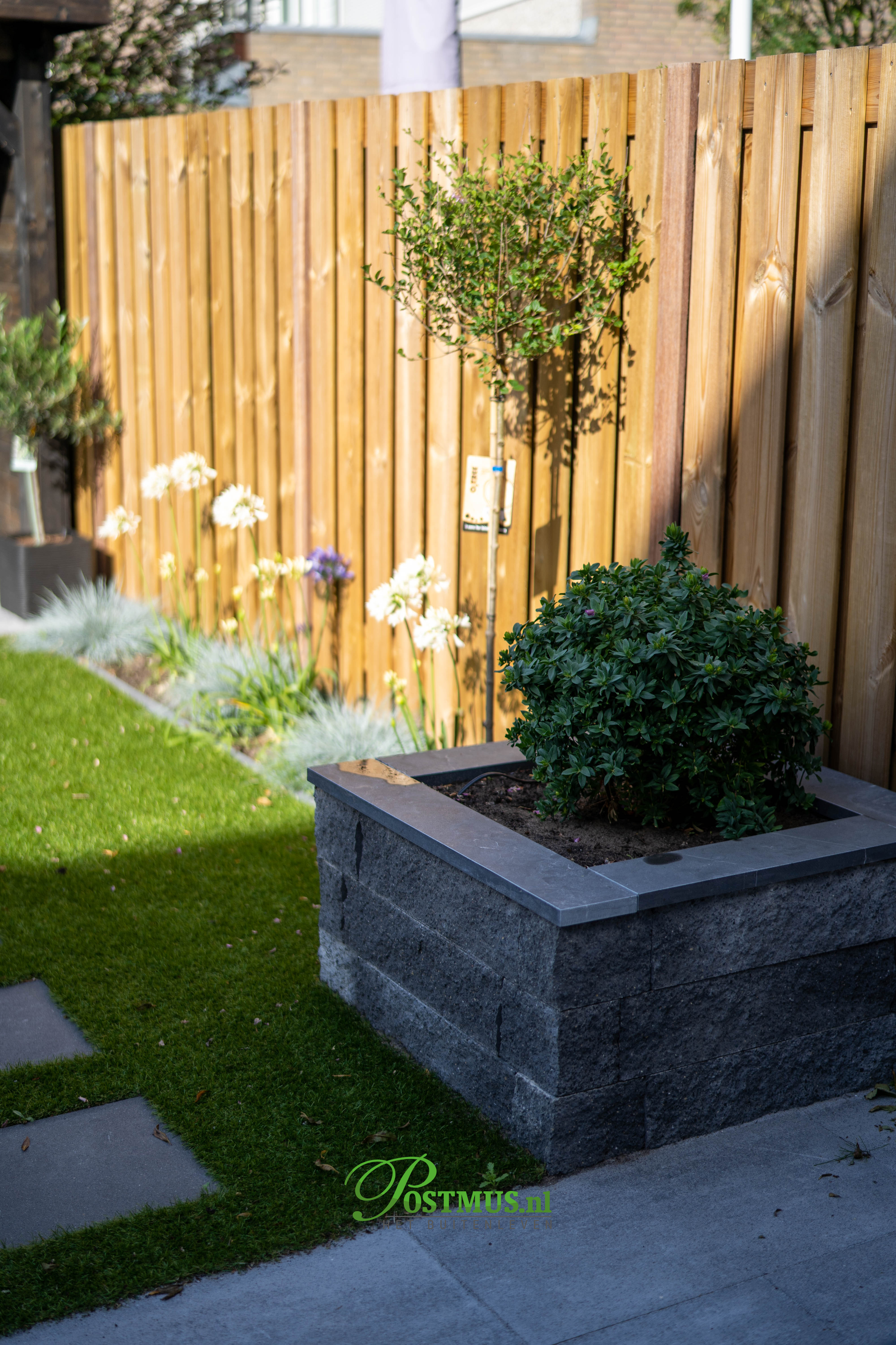 Vaderlijk zoete smaak karakter Sfeervolle tuin met plantenbakken en veranda | Postmus Sierbestrating Vaderlijk zoete smaak karakter Sfeervolle tuin met plantenbakken en veranda | Postmus Sierbestrating